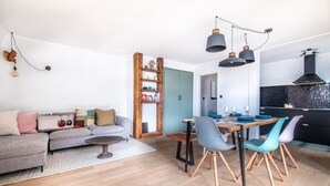Uma sala de estar moderna com sofá, mesa de jantar, cadeiras e uma cozinha equipada com fogão e armários.