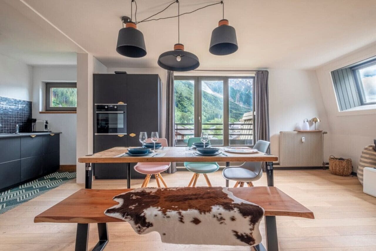 Une cuisine moderne avec un coin repas, de grandes fenêtres et une vue sur l’extérieur.