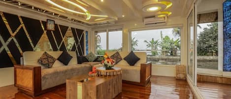 Un salón moderno con un sofá modular, una mesa de centro de madera y un amplio ventanal con vistas a zonas verdes.