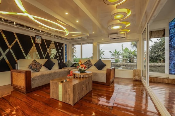 Un salón moderno con un sofá modular, una mesa de centro de madera y un amplio ventanal con vistas a zonas verdes.