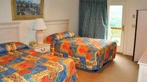 Two single beds are covered with colorful quilts, accompanied by a nightstand with a lamp and telephone.