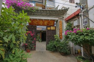 Un patio chino tradicional con tejado de baldosas, plantas en macetas y una puerta de madera.