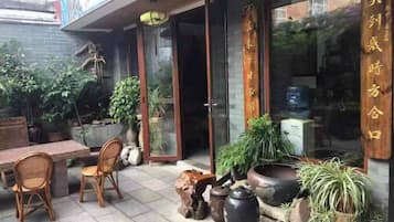 An outdoor seating area with wicker furniture, potted plants, and a wooden table.