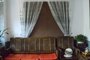 A room with a traditional sofa set, a small table, and a potted plant. - Han Shu Xiang Yuan Hostel (Jianshui)