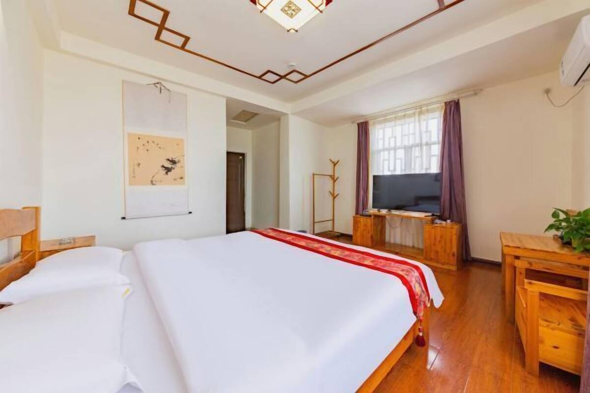 A hotel room with a large bed, a desk, a television, and a window with curtains.