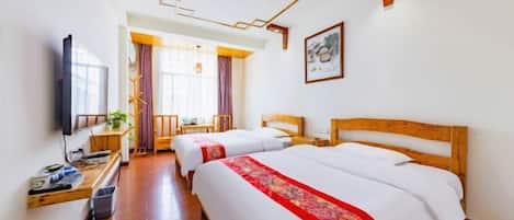 A hotel room with two beds, a TV, a desk, and a window with curtains.