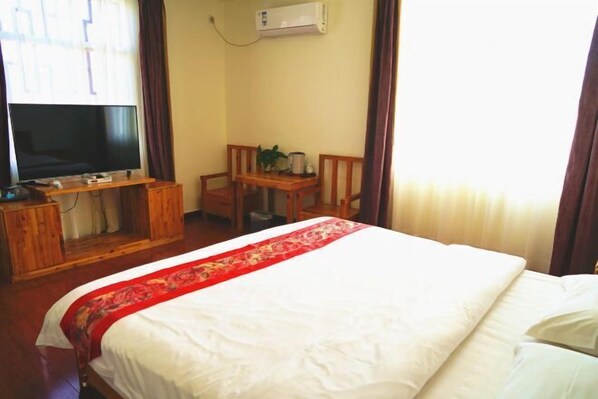 A hotel room with a bed, a TV, a wooden desk, and a chair. - Han Shu Xiang Yuan Hostel (Jianshui)