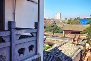 A traditional building with a balcony, a view of a cityscape, and a body of water in the distance. - Han Shu Xiang Yuan Hostel (Jianshui)