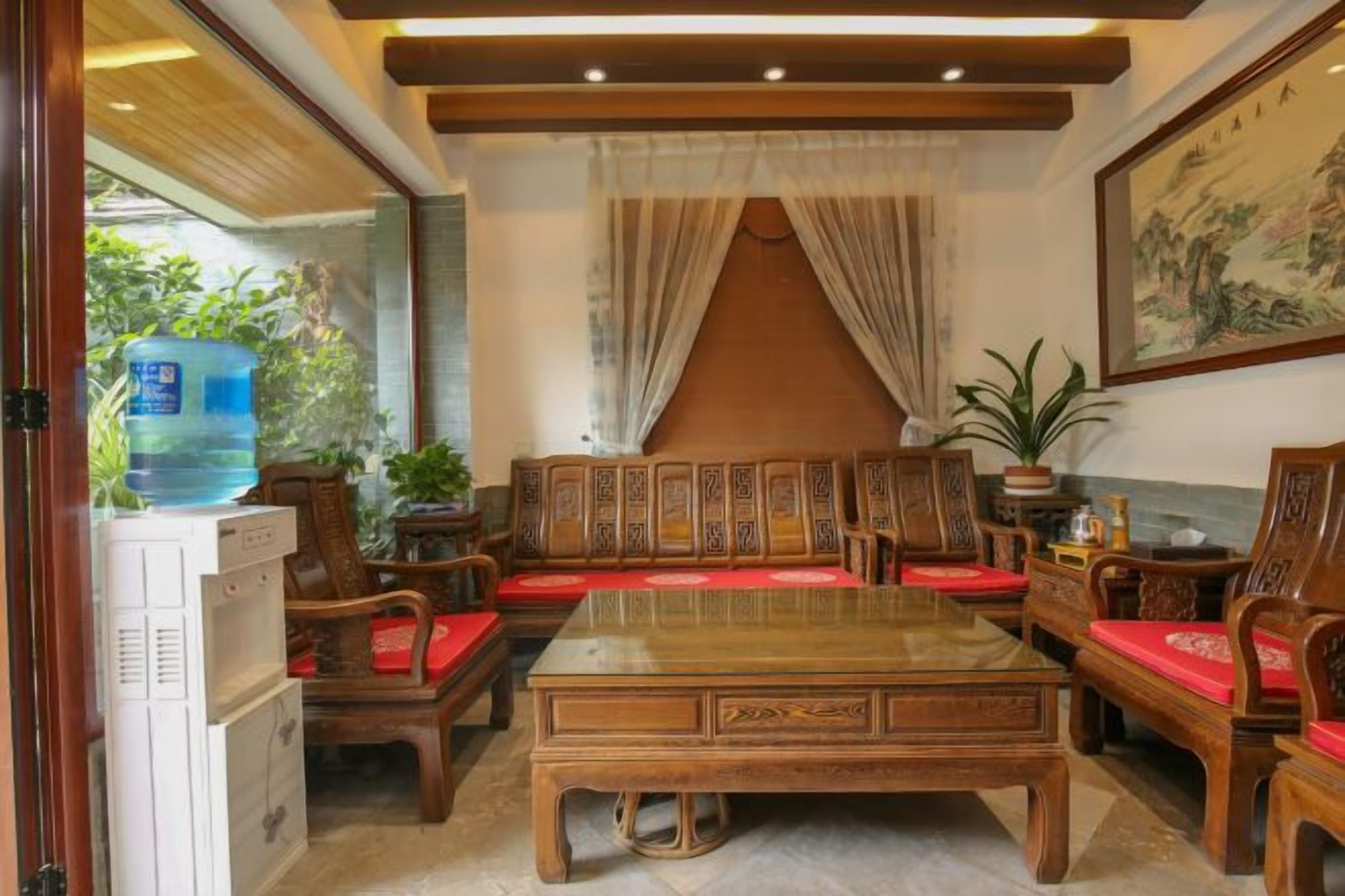Un salón de estilo tradicional con una mesa de centro de madera, sofás con cojines rojos y un dispensador de agua grande.