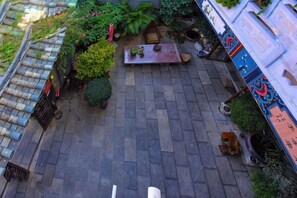 A courtyard with a tiled floor, potted plants, a bench, and a small table. - Han Shu Xiang Yuan Hostel (Jianshui)