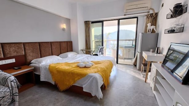 A hotel room with a bed, a desk, a TV, and a balcony with a view. - Xiamen Enfen Hotel (Xiamen)