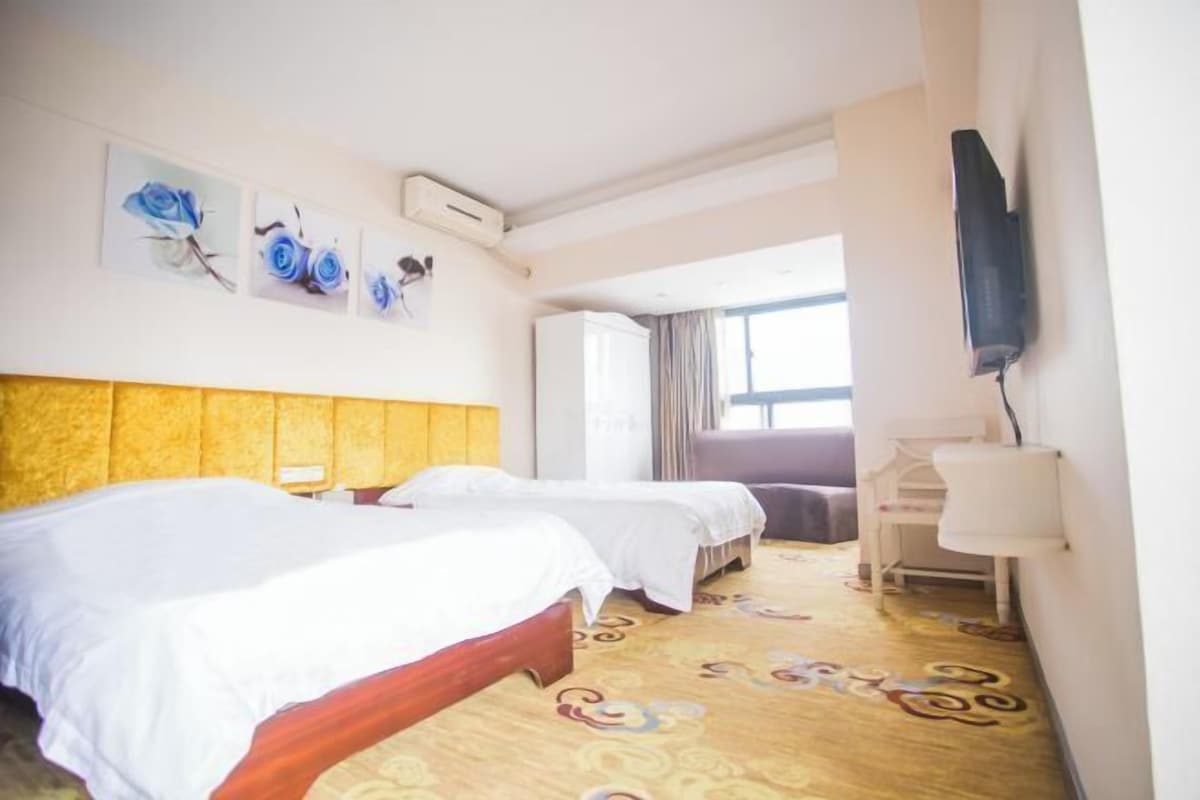A hotel room with two beds, a TV, and a desk.