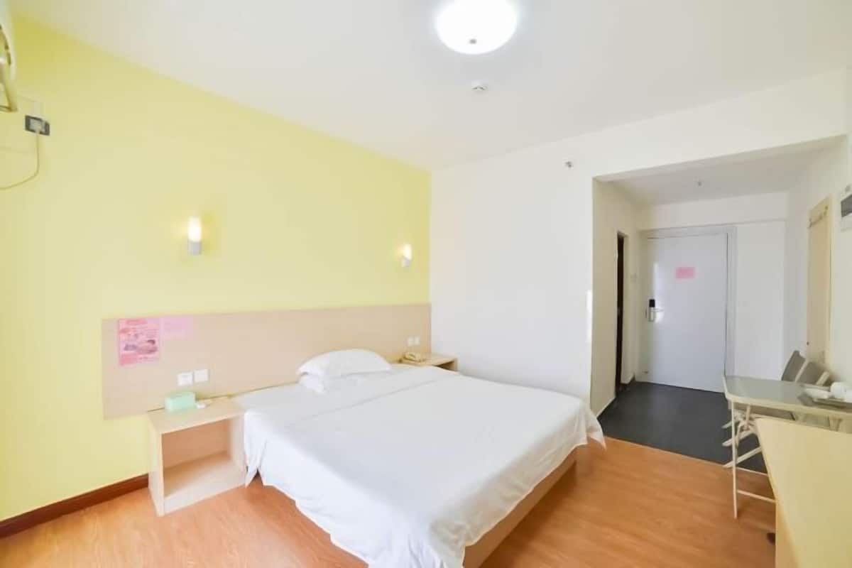 Cozy retreat with a single bed, bedside table, and desk, perfect for a relaxing stay.