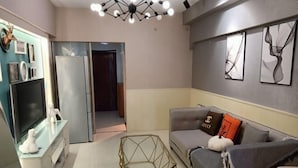 A modern living room with a sofa, a glass coffee table, a TV, and a refrigerator. - Xiamen Enfen Hotel (Xiamen)