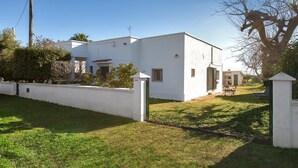 Un edificio moderno de color blanco con techo plano, un pequeño porche y un césped bien cuidado.