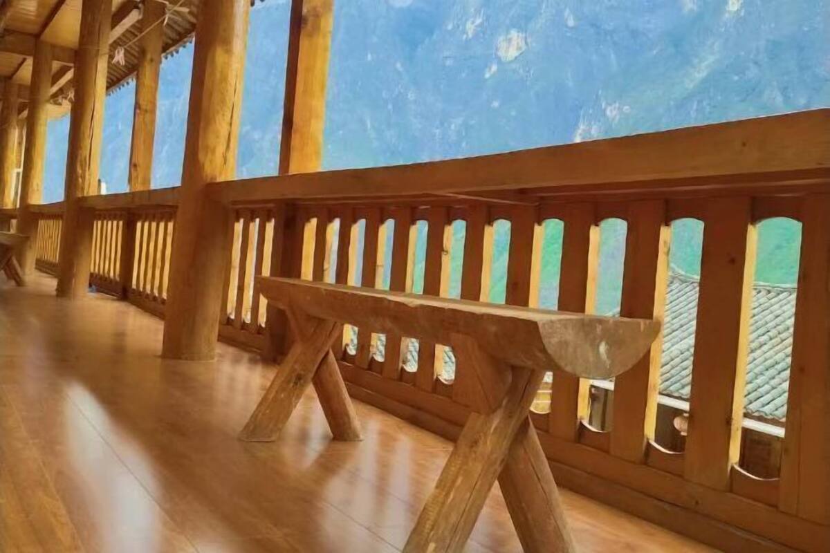 Interior de madera con un banco, columnas de madera y vistas a través de una ventana.