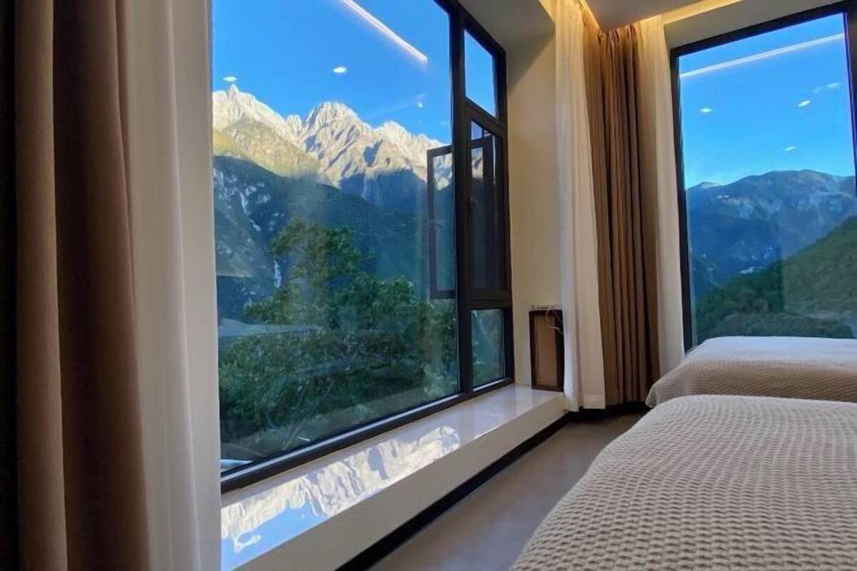 Habitación de hotel con un ventanal grande que ofrece vistas a la montaña.