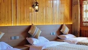 Habitación de hotel con paneles de madera, una cama con ropa de cama estampada y una lámpara fijada a la pared.