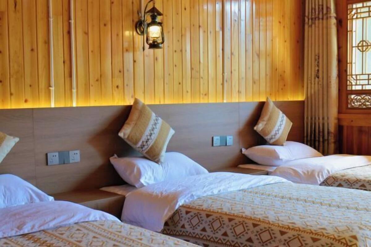 Habitación de hotel con paneles de madera, una cama con ropa de cama estampada y una lámpara fijada a la pared.