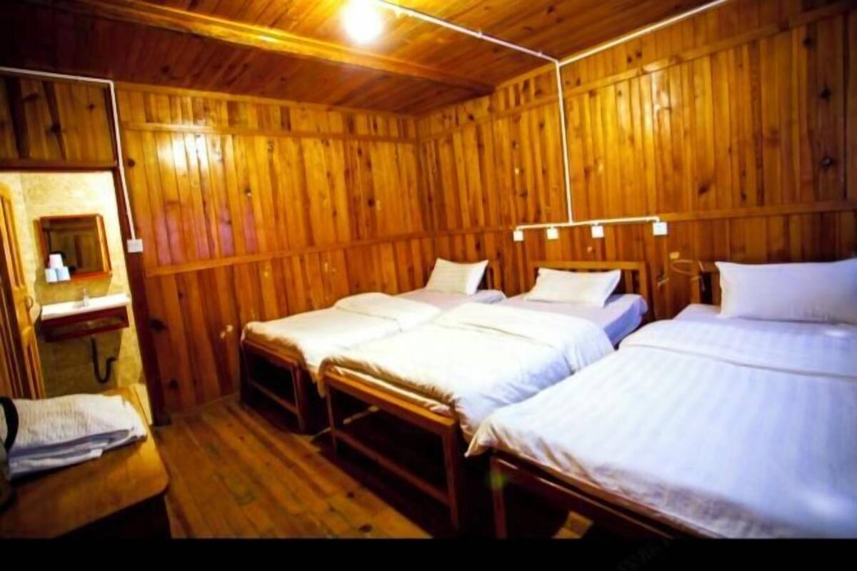 Una cabaña de madera con tres camas, una mesita y un espejo.