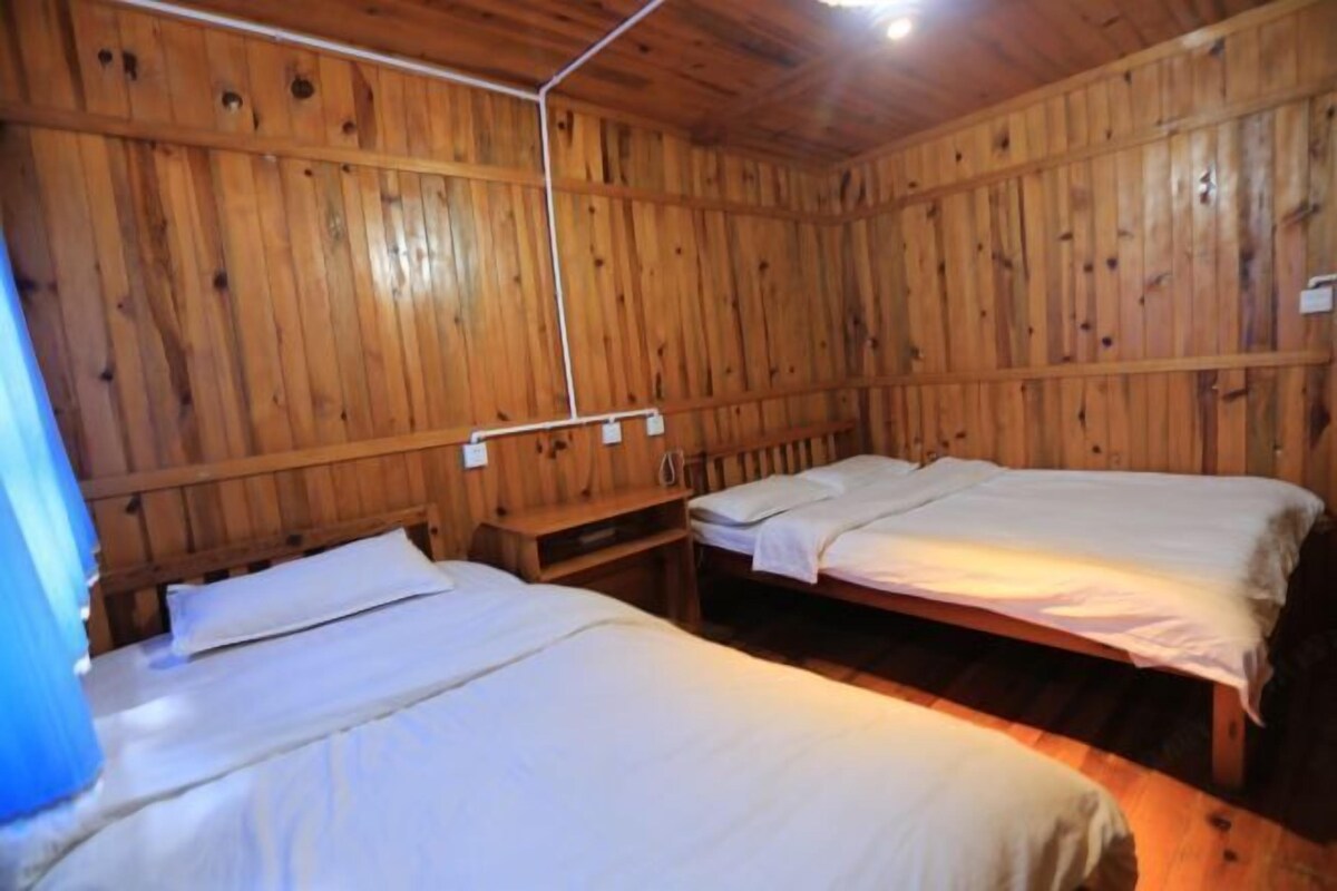 Een houten kamer met twee bedden, een houten plafond en een kleine tafel.