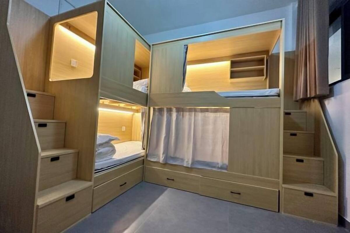 Habitación con literas compactas y de varios niveles, cajones de almacenamiento integrados y una pequeña zona de estar.