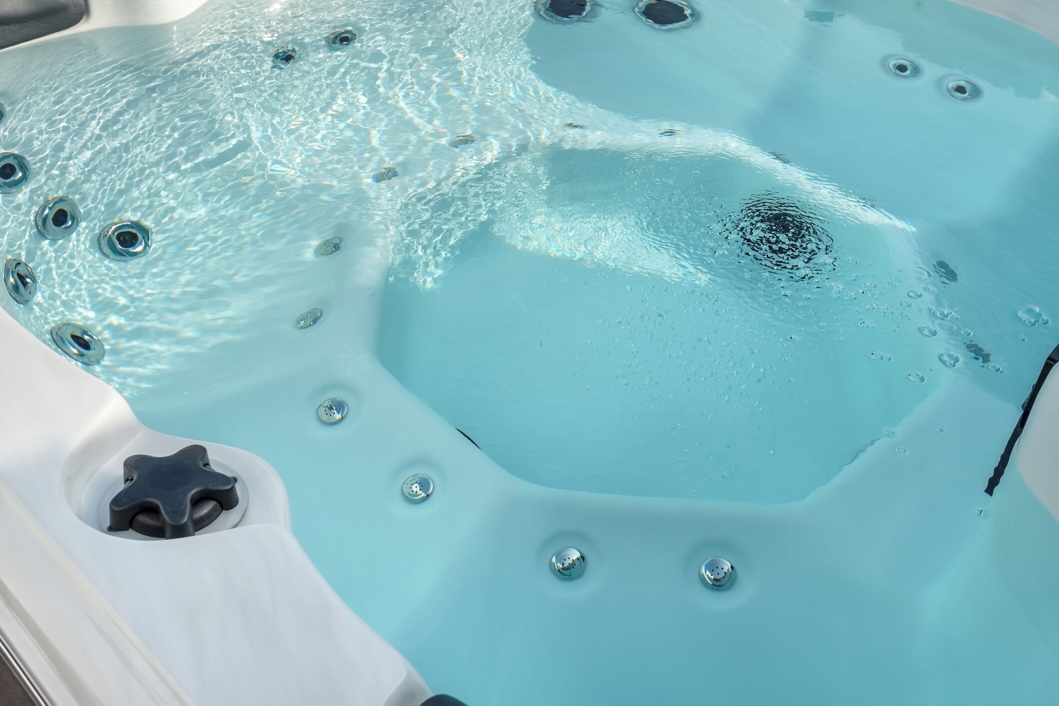 Ein Whirlpool mit klarem Wasser, Blasen und einem sternförmigen Abfluss.