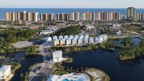 Vue aérienne d’un complexe hôtelier situé sur la côte, comprenant plusieurs bâtiments, une grande piscine et un port de plaisance.