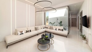 A modern living room with a sectional sofa, a round coffee table, and a TV mounted on the wall. - Villa El - Luxury villa for an exclusive vacation in Crete (Kournás)