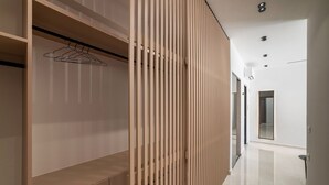 A modern interior with a wooden wardrobe, a hanging rack, and a sleek corridor leading to a door. - Villa El - Luxury villa for an exclusive vacation in Crete (Kournás)