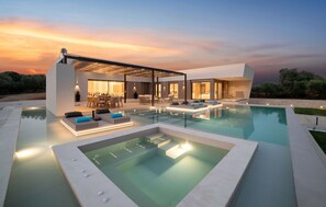 Uma casa moderna com piscina, área de estar externa e um alpendre coberto.