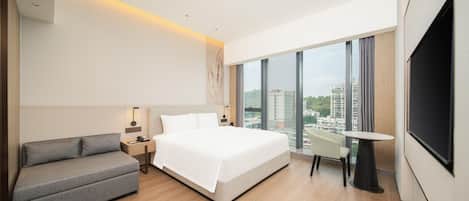 Une chambre d’hôtel moderne avec un grand lit, un canapé, une petite table et un téléviseur.