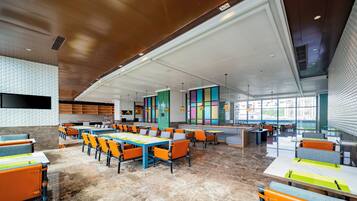 A spacious indoor area with multiple seating arrangements, a large window providing natural light, and a modern architectural design.