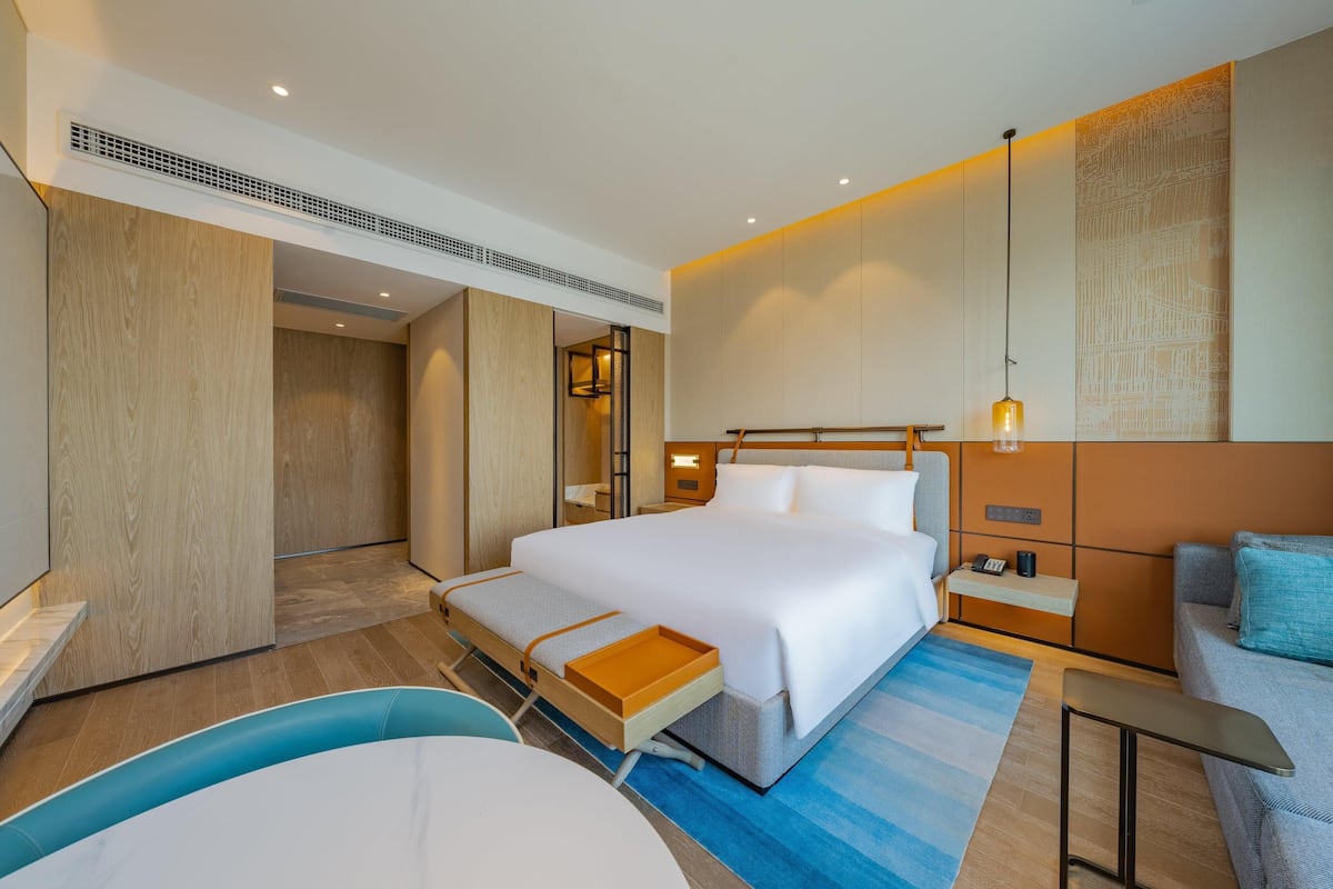 Ein modernes Hotelzimmer mit einem großen Bett, Nachttischen, einem Schreibtisch und einer Sitzecke.