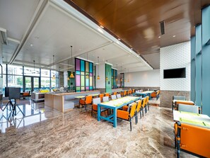 A modern dining area with a long table, orange chairs, and a bar counter. - Holiday Inn Zhuhai City Center (Zhuhai)