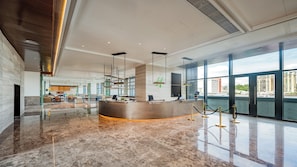 A hotel lobby with a reception desk, seating area, and large windows offering city views. - Holiday Inn Zhuhai City Center (Zhuhai)