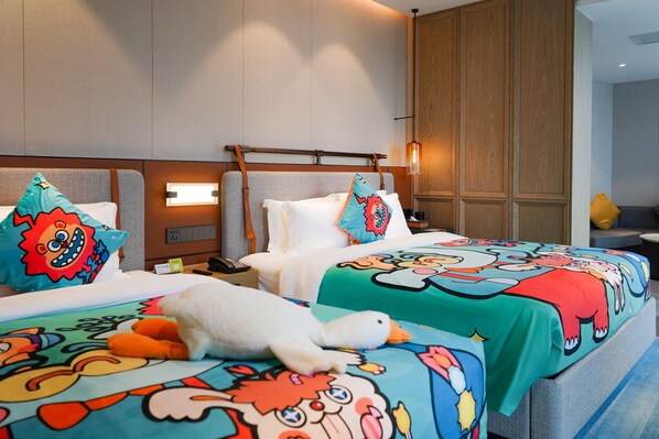 Una habitación de hotel con dos camas, cada una con ropa de cama temática de dibujos animados y un patito de peluche en una de ellas, y un armario de madera al fondo.