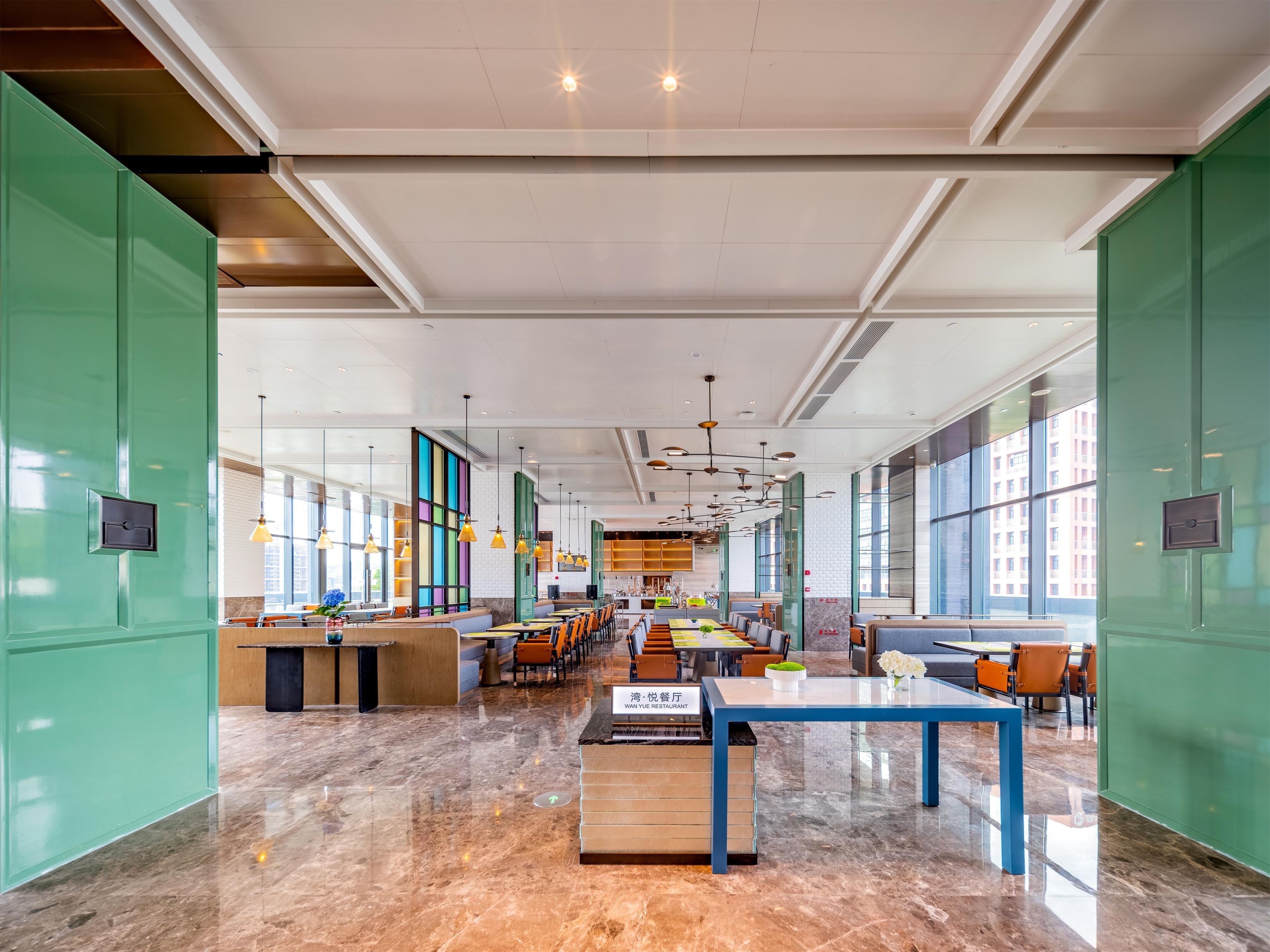 A spacious restaurant with high ceilings, large windows, and a modern interior design.