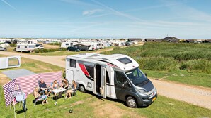 A caravan park with multiple caravans and a family dining outside one. - First Camp Lakolk strand- Römö (Rømø)