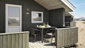 A wooden building with a door, a window, and a table with chairs. - First Camp Lakolk strand- Römö (Rømø)