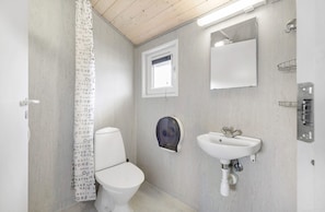 Bathroom features a toilet, sink, and shower area with a patterned curtain.