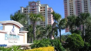 A hotel with a prominent sign, multiple floors, and palm trees in the foreground.