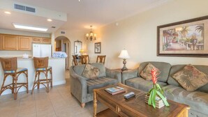 A living room with a sofa, two armchairs, a coffee table, and a dining area with chairs and a table.