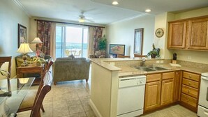 A compact kitchen with a dishwasher, wooden cabinets, and a dining area with a table and chairs.