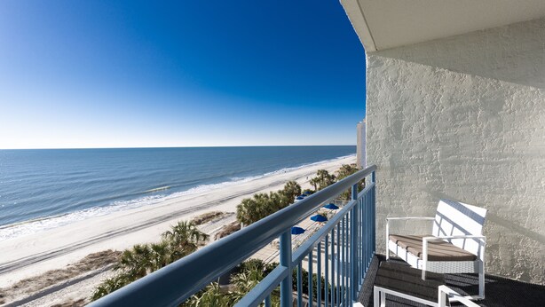 Un balcon avec vue sur la plage et l’océan.
