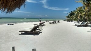 A beach with sun loungers and palm trees. - TreeHouse EcoChic/3 min walk beach/Wifi/AC/kitchen/King Size Bed (Isla Holbox)