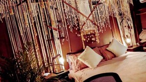 A room with a thatched roof, a bed with pillows, a chair, and a hanging macrame decoration. - TreeHouse EcoChic/3 min walk beach/Wifi/AC/kitchen/King Size Bed (Isla Holbox)