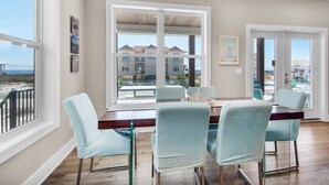Un comedor con un ventanal grande, una mesa de madera y sillas azul claro.