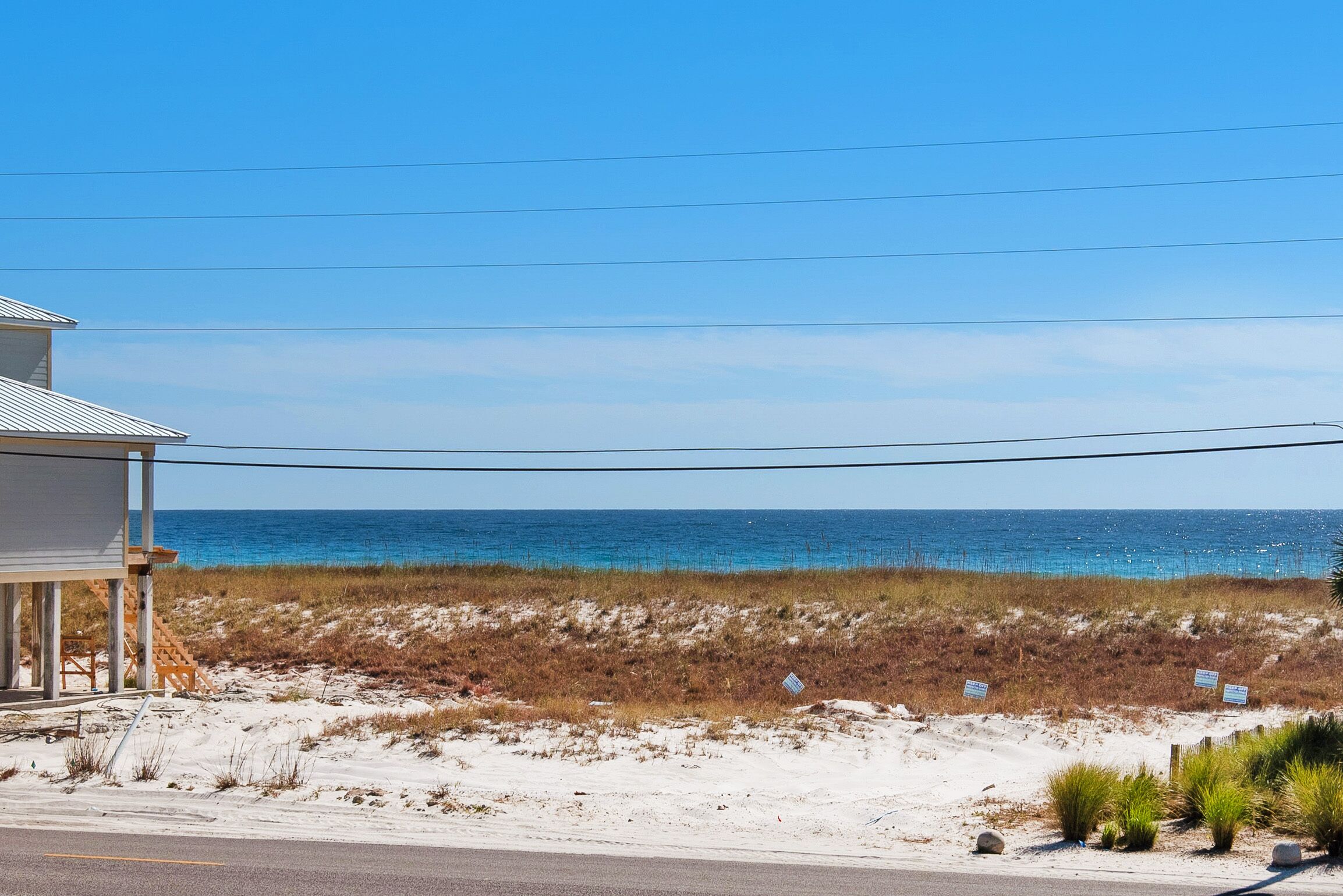 A beachfront property with a sandy beach, ocean view, and a building with a porch.