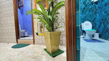 A bathroom with a toilet, a sink, and a large potted plant.